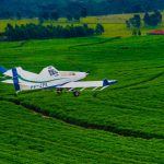 Foto de aeronave sobrevoando plantação para realizar pulverização de defensivos agrícolas